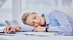 Tired young caucasian business woman sitting at desk and sleeping. Exhausted young female professional taking a nap lying her head on the table
