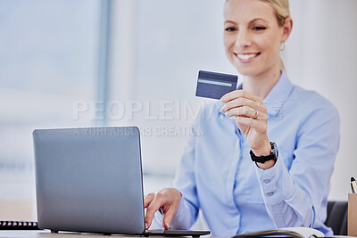 Closeup of caucasian woman reading her credit card while using her laptop to shop online while sitting in the office at work. Shopping has never been simpler or more convenient