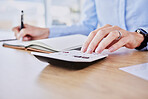 Close up of female hands using calculator and making notes at desk. Business woman making calculations while writing in notebook in office