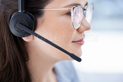Closeup of one confident young caucasian call centre telemarketing agent wearing glasses and talking on headset while working in office. Face of female consultant operating helpdesk for customer service and sales support