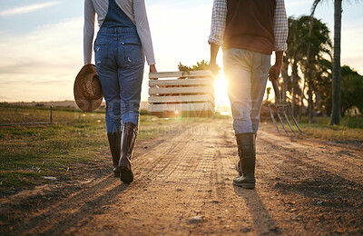 Buy stock photo Two farmers carrying a vegetable basket together on a sunny morning. Unrecognisable couple walking with fresh organic produce on a dirt road