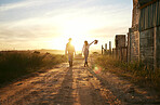 Two farmers carrying a basket of fresh produce and walking against a sunset background. Unrecognisable woman celebrating successful harvest on a farm with male colleague