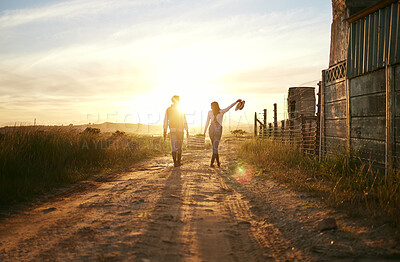 Buy stock photo Two farmers carrying a basket of fresh produce and walking against a sunset background. Unrecognisable woman celebrating successful harvest on a farm with male colleague