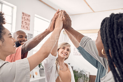 Group of five happy diverse businesspeople giving each other a high five in an office at work. Business professionals having fun joining their hands in support and unity during a meeting