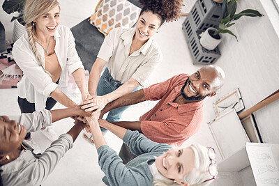 Group of five cheerful diverse businesspeople piling their hands together in an office at work. Happy business professionals having fun standing with their hands stacked for support and unity