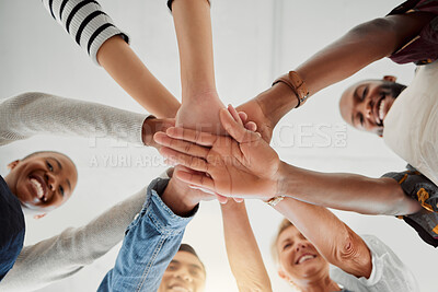 Buy stock photo Group of happy clothing designers stacking their hands together in a shop at work. Tailors having fun standing with their hands piled for support and unity during a meeting at a boutique from below