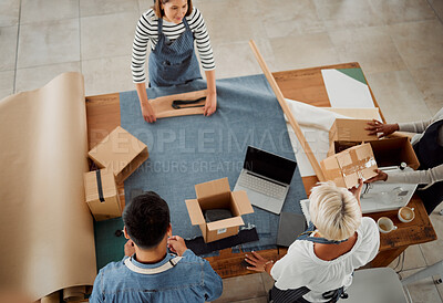 Buy stock photo Four diverse clothing designers packing their products working together at a table at work. Tailors making packages while working together from above. Colleagues packing products into boxes at a shop