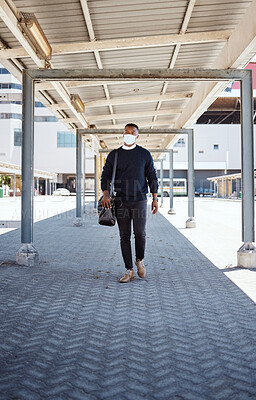Black businessman travelling alone.A african american businessman walking around town with his luggage while wearing mask to protect himself from the corona virus in the city