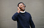 African american male on a phone call with his mobile device outside a building during the day while smiling Young black male talking on a phone while commuting to work