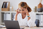 Young mixed race businesswoman suffering from a headache while working on a laptop in an office at work. One stressed hispanic businessperson suffering from anxiety and looking upset