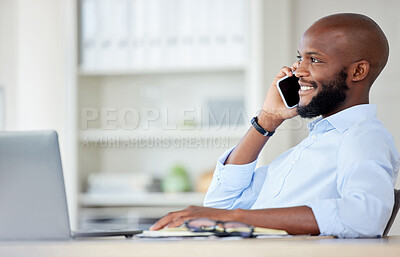 Young african american businessman on a call using a phone while working on a laptop in an office at work alone. One male business professional talking on a cellphone while working