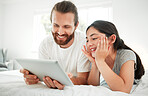 Happy caucasian father and daughter holding digital tablet while lying together on a bed. Teenage girl and dad watching movie online or playing game while spending time at home