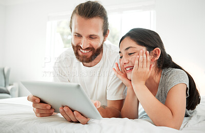 Buy stock photo Happy caucasian father and daughter holding digital tablet while lying together on a bed. Teenage girl and dad watching movie online or playing game while spending time at home