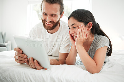 Buy stock photo Happy caucasian father and daughter holding digital tablet while lying together on a bed. Young girl and dad watching movie online or playing game while spending time at home