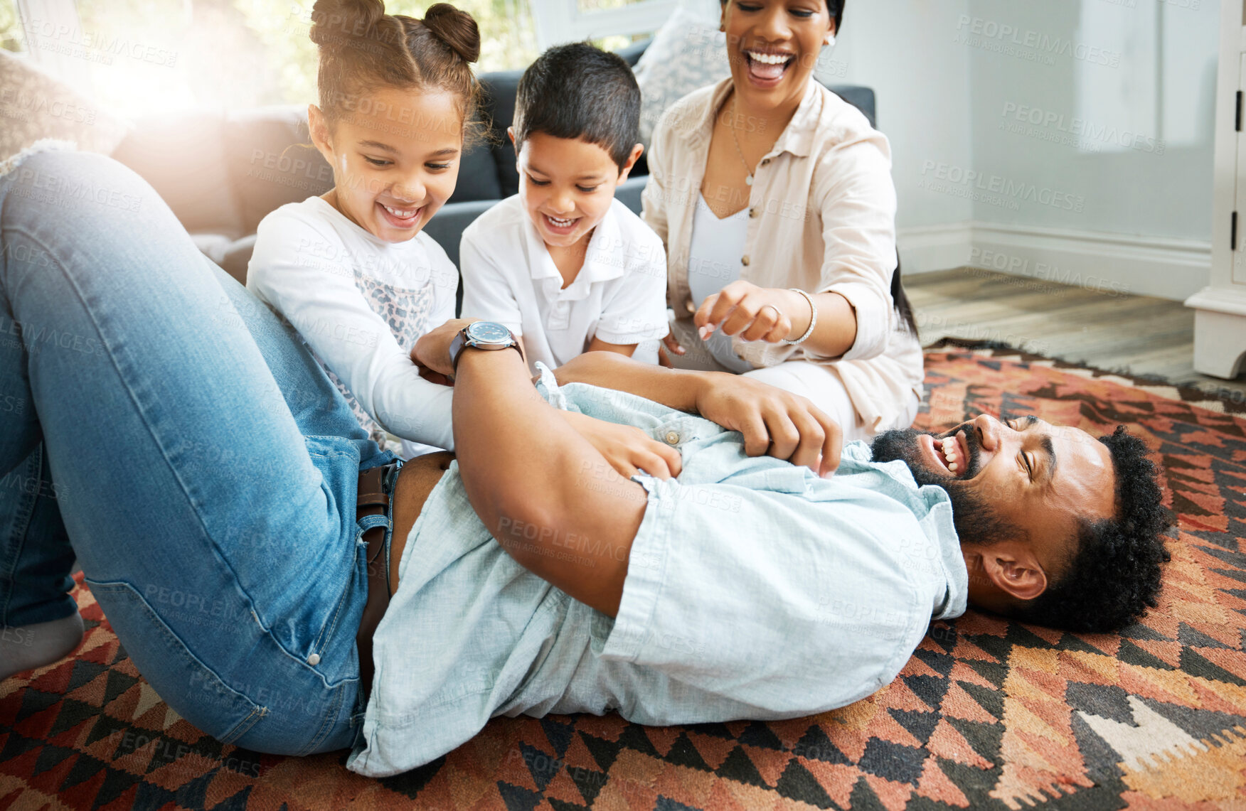 Buy stock photo Closeup of a young hispanic family playing together on the lounge floor at home. Mixed race father and mother having fun while playing with their cute little son and daughter in the lounge at home