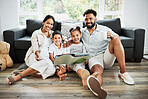 Mixed race family reading a book together on the floor at home. Hispanic mother and father teaching their little son and daughter how to read. Brother and sister learning to read with their parents