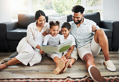 Mixed race family reading a book together on the floor at home. Hispanic mother and father teaching their little son and daughter how to read. Brother and sister learning to read with their parents