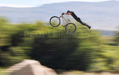 Buy stock photo Young man showing his cycling skills while out cycling on a bicycle outside. Adrenaline junkie practicing a dirt jump outdoors. Male wearing a helmet doing extreme sports with a mountain bike