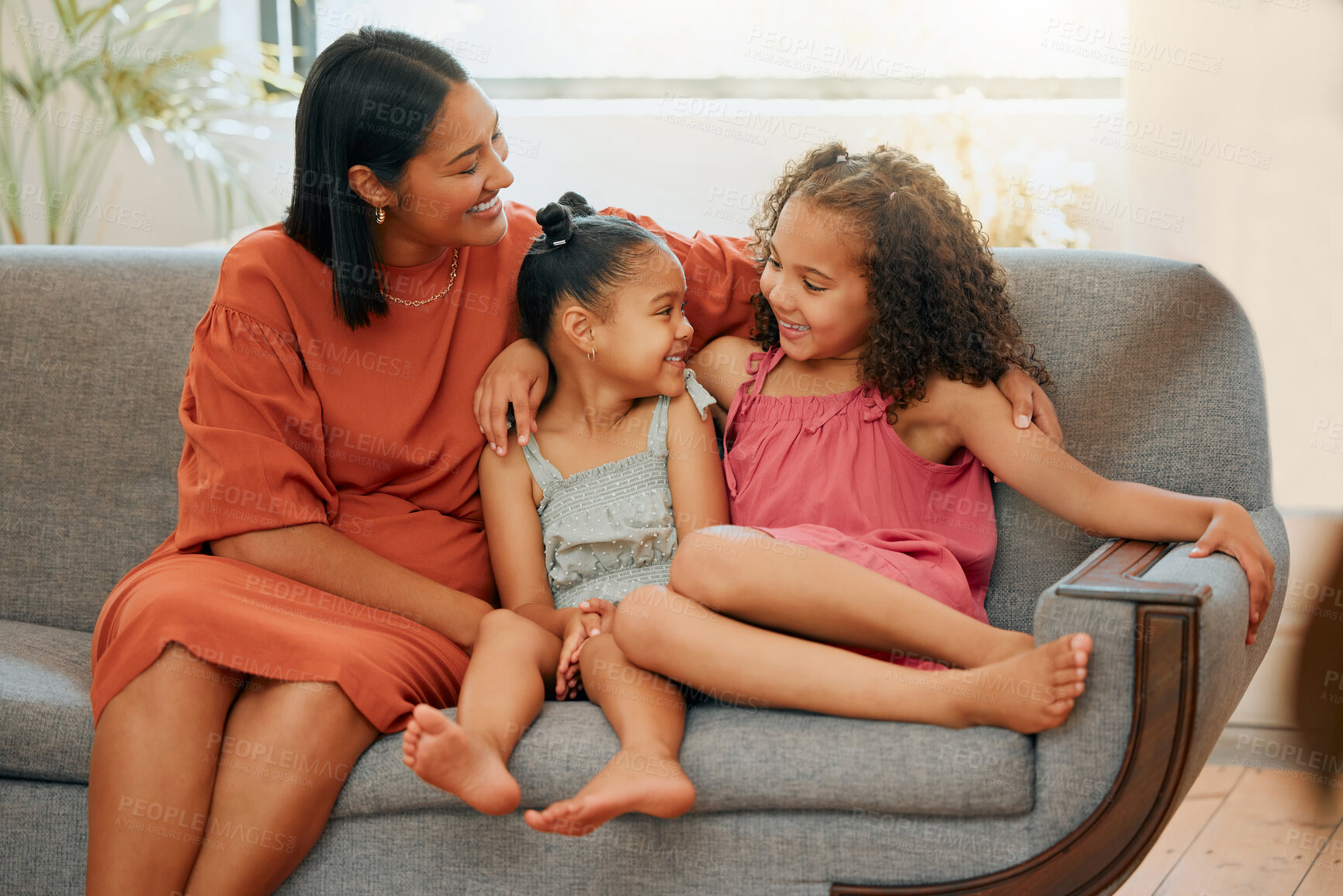 Buy stock photo A happy mixed race family of three relaxing in the lounge and sitting on the couch together. Loving black single parent bonding with her daughters while relaxing on a sofa at home