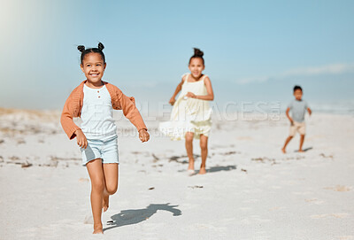 Buy stock photo Cheerful energetic little girl running and playing at the beach with her siblings following in the background.  Happy kids having a race on the beach
