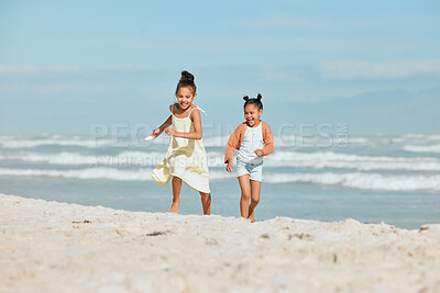 Buy stock photo Two adorable little mixed race girls running and having fun at the beach. Two sibling sisters playing on the shore collecting shells in the sand