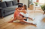 Loving caucasian couple being affectionate and enjoying romantic intimate moment while sitting on living room floor. Young woman sitting on top of boyfriend and gently kissing him on the forehead with her arms around him