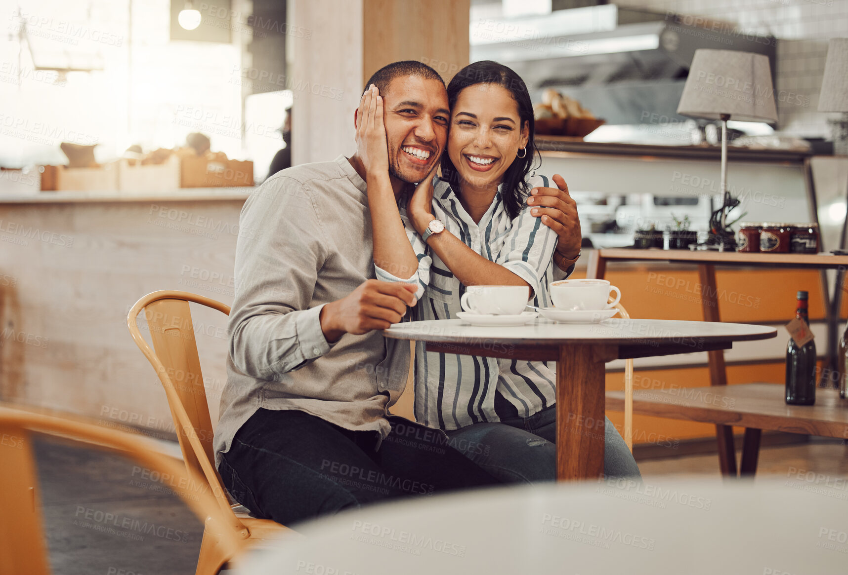 Buy stock photo Portrait of loving young mixed race couple having coffee while sitting at table in a cafe. Beautiful young woman holding her boyfriends face and smiling while looking at the camera on their date