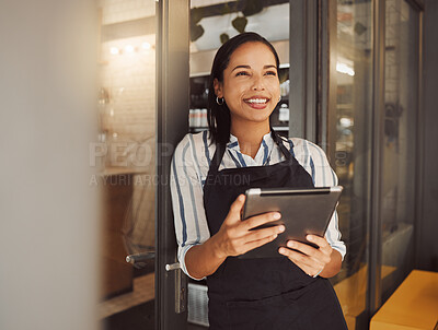 Happy businesswoman using a digital tablet in her shop. Business owner standing in her shop entrance. Entrepreneur ordering stock on an online app. Boss standing in grocery store entrance