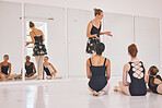Young woman dance instructor teaching a ballet class to a group of a children in her studio. Ballerina teacher working with girl students, preparing for their recital, performance or upcoming show