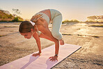 Full length yoga woman holding crow pose in outdoor practice in remote nature. Beautiful caucasian person using mat, balancing on hands while stretching alone at sunset. Young, active, zen and serene