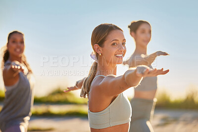 Diverse smiling yoga women in warrior pose during outdoor practice in remote nature. Group of happy active friends bonding and balancing while stretching at sunset. Beautiful young active zen people