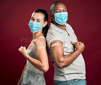 Buy stock photo Covid vaccinated African american man and mixed race woman standing back to back. Two people wearing surgical face mask isolated against red background in studio with copyspace. Flexing plaster on arm