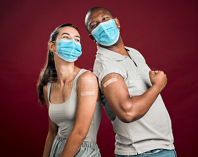 Buy stock photo Covid vaccinated African american man and mixed race woman standing back to back. Two people wearing surgical face mask isolated against red background in studio with copyspace. Showing plaster on arm