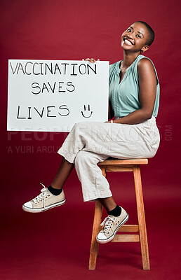 Buy stock photo African american covid vaccinated woman showing and holding poster. Portrait of smiling black woman isolated against red studio background with copyspace. Model promoting corona vaccine with sign