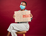 African american covid vaccinated woman showing, holding poster and wearing surgical face mask. Happy black model isolated on red studio background with copyspace. Promoting corona vaccine with sign