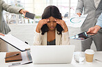 Young african american businesswoman suffering from a headache while using a laptop and working in a demanding environment. Stressed businessperson looking tired while working with a group of colleagues at work