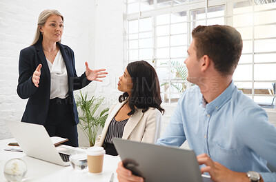 Buy stock photo Mature caucasian businesswoman talking to her young colleagues in a meeting together at work. Three businesspeople planning and discussing while in an office together