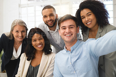 Group of cheerful diverse businesspeople taking a selfie together at work. Happy young caucasian businessman taking a photo with his content colleagues in an office. Coworkers bonding at work