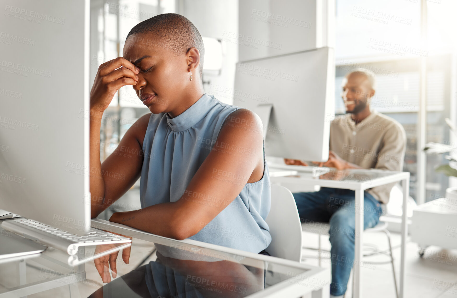 Buy stock photo Young stressed african american businesswoman suffering from a headache while working on a desktop computer at work. One unhappy black female businessperson suffering from anxiety while working on a computer at a desk in an office