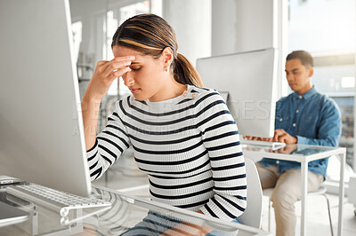 Buy stock photo Young stressed mixed race businesswoman suffering from a headache while working on a desktop computer at work. One unhappy hispanic female businessperson suffering from anxiety while working on a computer at a desk in an office