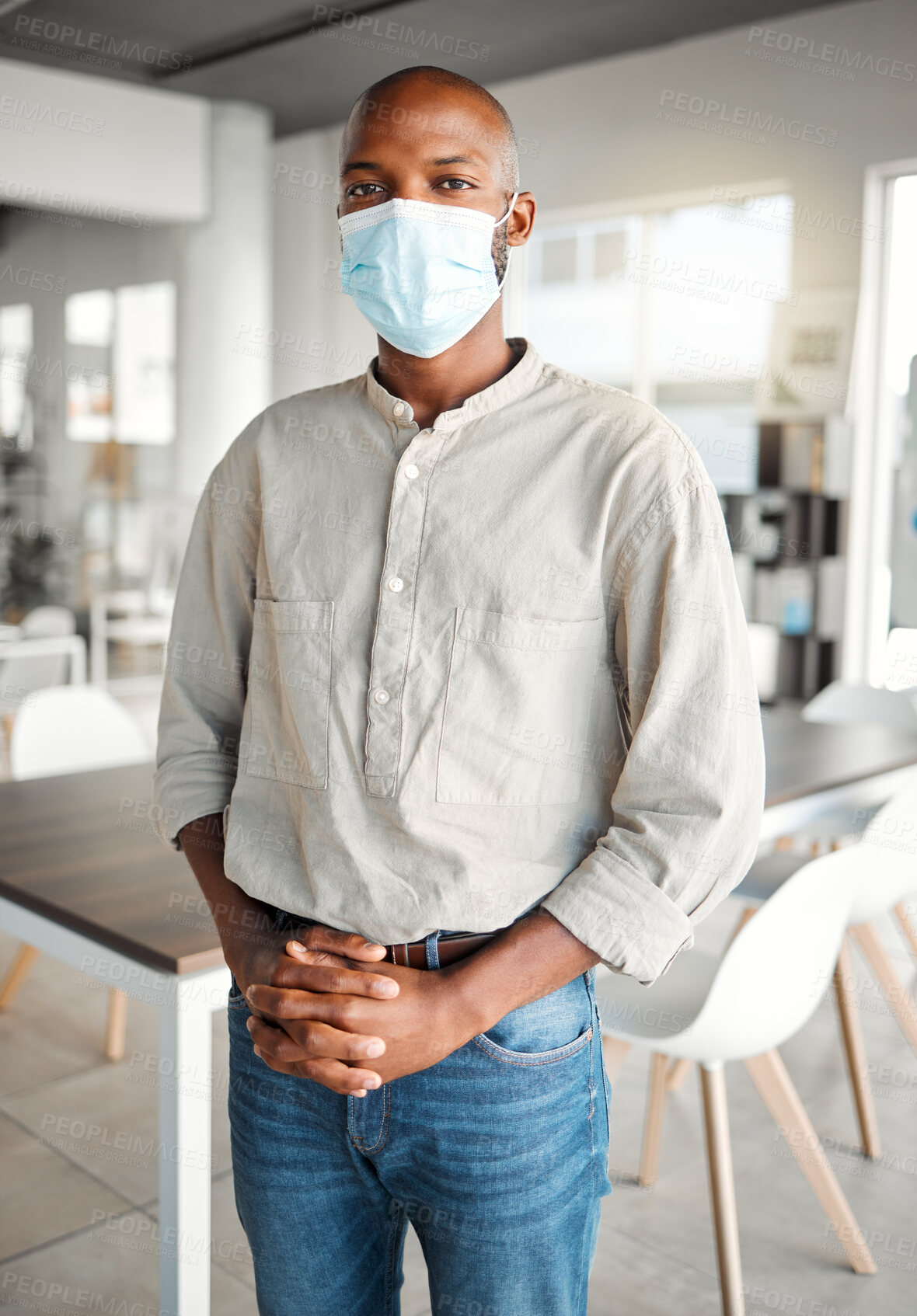 Buy stock photo Young african american businessman standing in an office wearing a mask at work. Male business professional wearing a mask protecting from a virus and standing in an office at work