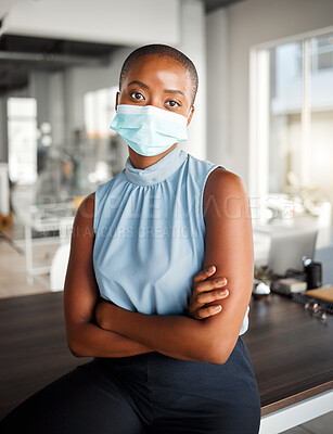 Buy stock photo Young african american businesswoman standing with her arms crossed and wearing a mask at work. One confident black female boss wearing a mask protecting from a virus and standing at work