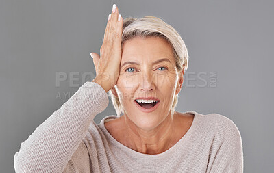 Buy stock photo Thinking, idea or memory with a senior woman knocking her head with her hand to remember or forget in studio on a grey background. Face portrait of a model with grey hair having a light bulb moment