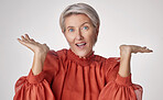 One mature caucasian woman isolated against a grey copyspace background posing with her hands up and feeling unsure. Portrait of senior woman making facial expressions while thinking