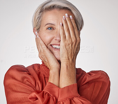 Buy stock photo Eye, half and smile of a senior woman isolated against a grey background in a studio. Portrait of an elderly model lady in beauty with hands over her face in wellness, health and teeth. 