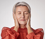 One mature woman suffering with a headache and looking stressed while posing against a grey copyspace background. Ageing woman experiencing anxiety and fear in a studio