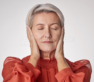 Buy stock photo One mature woman suffering with a headache and looking stressed while posing against a grey copyspace background. Ageing woman experiencing anxiety and fear in a studio