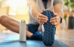 Closeup of one active caucasian man touching his feet and stretching legs for warmup to prevent injury while exercising at home. Bottom sole of shoes of guy preparing for training workout  on a mat on the floor