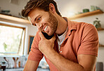 Young caucasian businessman on a call using a cellphone while working from home alone. Happy male businessperson talking on a cellphone while working in the kitchen at home