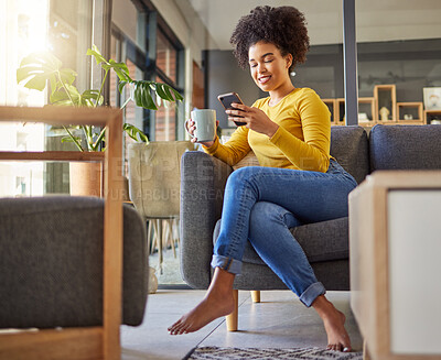 Buy stock photo African woman, texting and phone on living room sofa, coffee and smile for chat, contact or meme on web. Girl, smartphone and reading on social media app, blog or video on internet on lounge couch